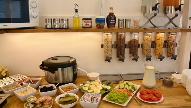 A buffet setup with various food items, condiments, and a food processor. - Vila Bohemia (Prague)