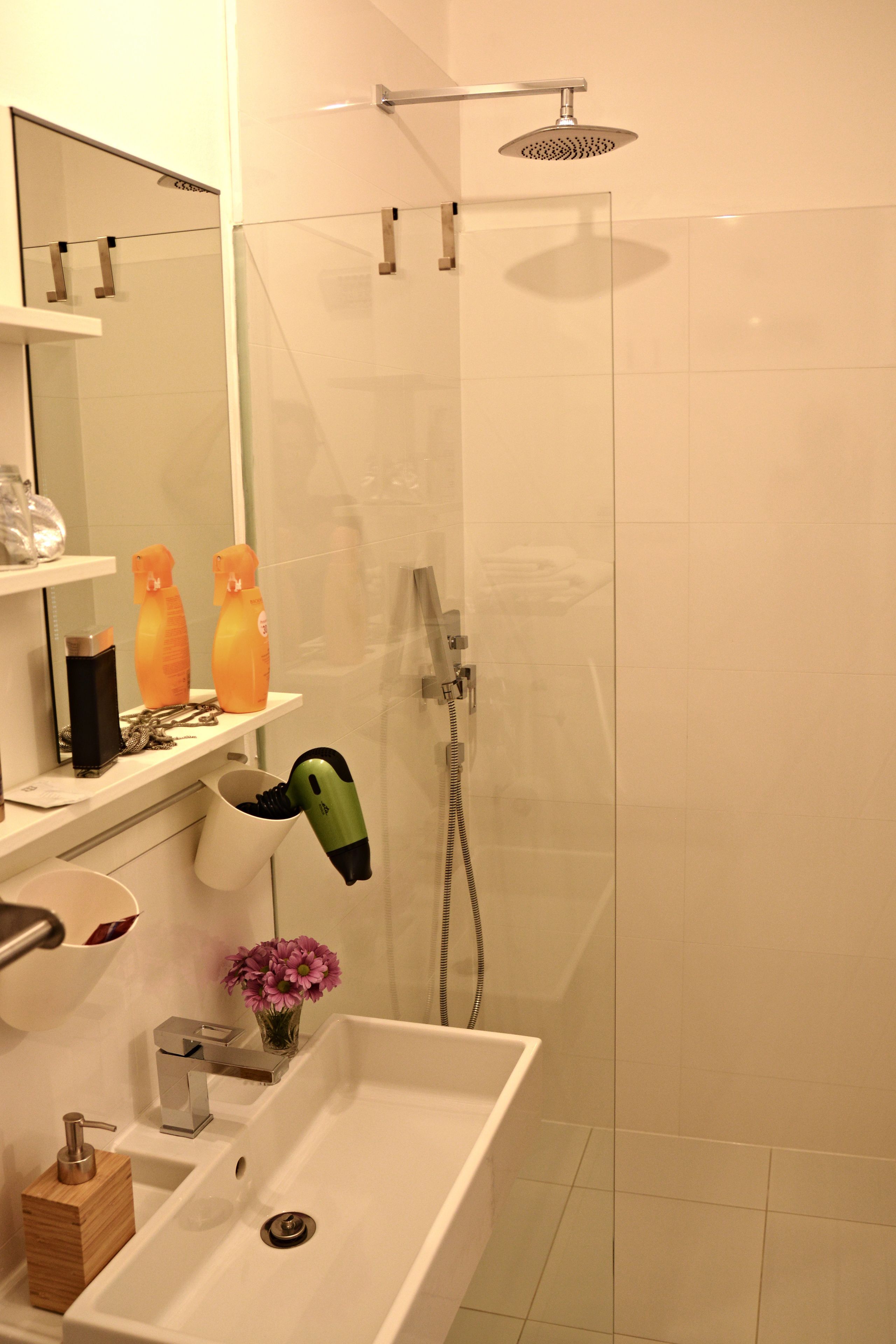 Un baño moderno con ducha, lavabo y espejo.