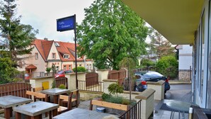 An outdoor patio area with stone tables and benches, a flag, and a view of a residential building in the background. - Vila Bohemia (Prague)
