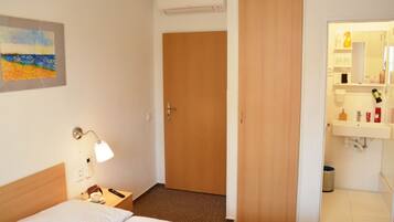 Ett hotellrum med en säng, ett nattduksbord, en lampa och en tavla på väggen.