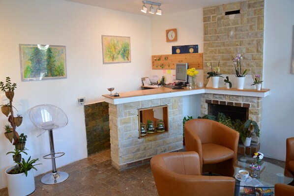 A modern interior with a stone fireplace, a wooden reception desk, and leather chairs.