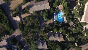 An aerial view of a residential area with a swimming pool surrounded by trees and a few houses.