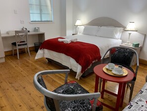 A neatly arranged bedroom with a bed, two bedside lamps, a desk, and a chair. - Savoy Hotel Beaufort-West (Beaufort West)