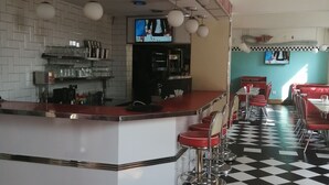 A diner with a checkered floor, bar stools, and a counter with signs for 'Fries', 'Joes Breakfast', 'Combo plates', and 'Take away'. - Savoy Hotel Beaufort-West (Beaufort West)