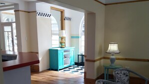 A spacious room with wooden flooring, a dining area with a table and chairs, a kitchen with a counter, and a view through an arched doorway. - Savoy Hotel Beaufort-West (Beaufort West)