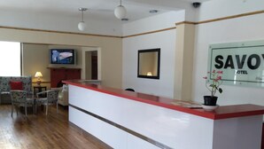A hotel reception area with a long counter, a television mounted on the wall, and a sign that reads "SAVO HOTEL". - Savoy Hotel Beaufort-West (Beaufort West)
