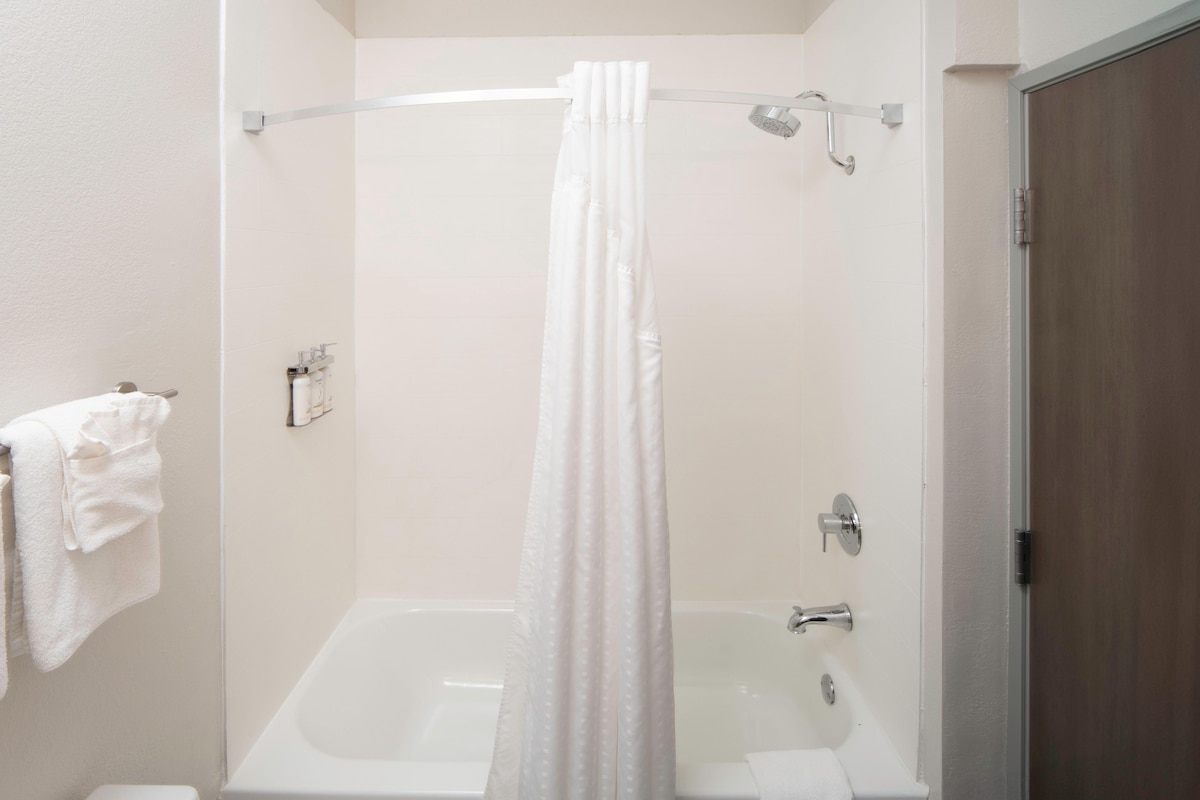 A bathroom with a bathtub, a shower curtain, and a towel rack.