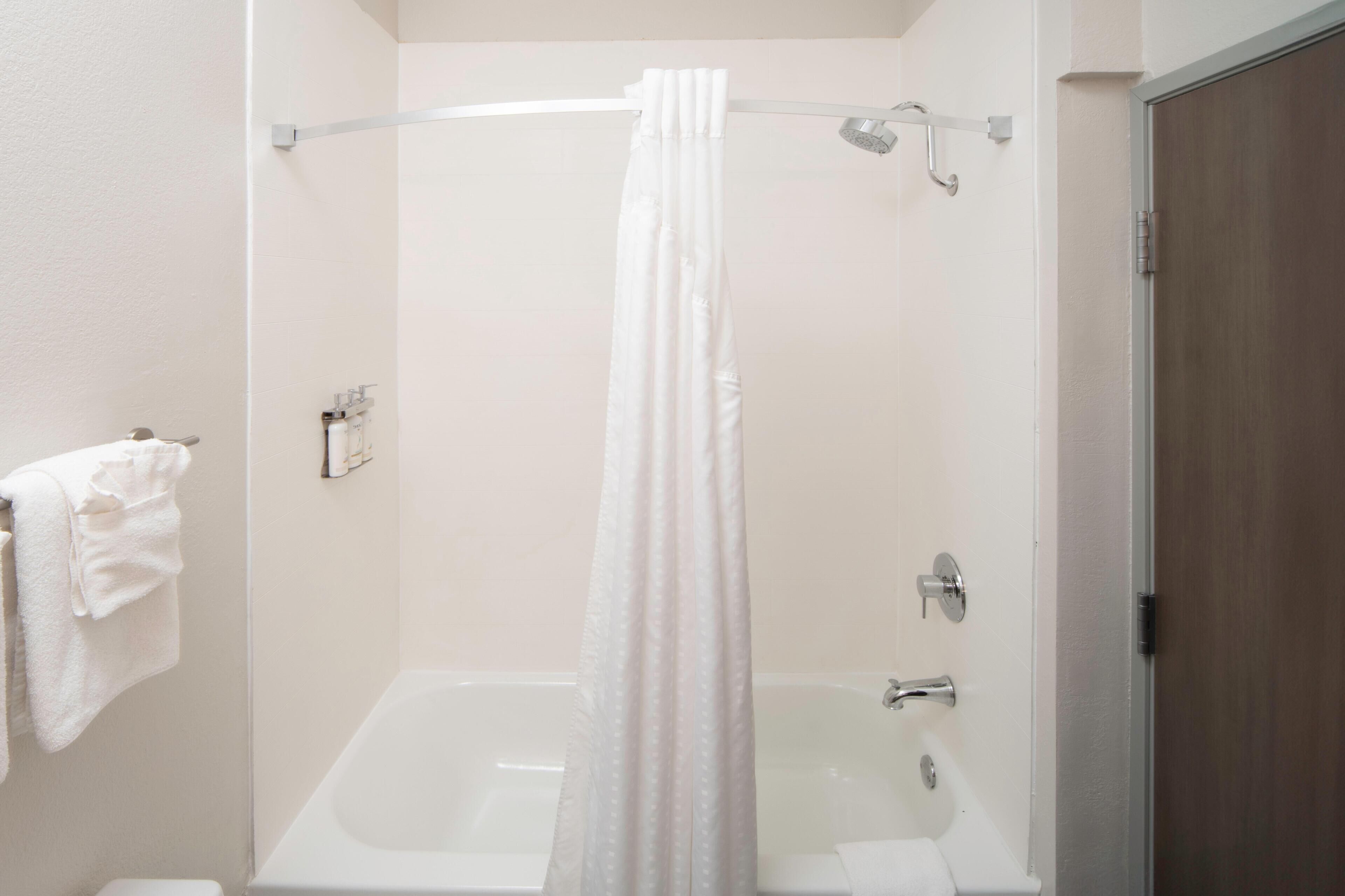A bathroom with a bathtub, a shower curtain, and a towel rack.