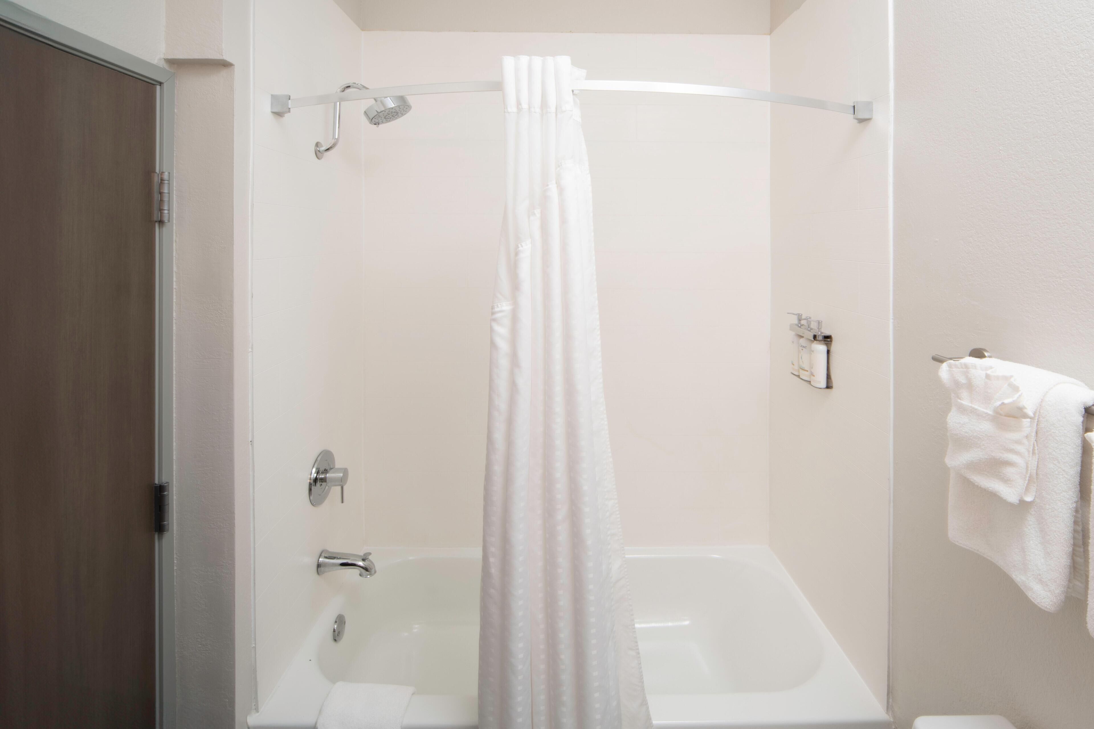 A bathroom with a bathtub, a shower curtain, a towel rack, and a toilet.