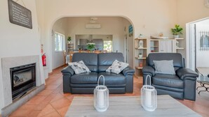 Ein Wohnzimmer mit Kamin, zwei Sofas und einer Küche im Hintergrund.