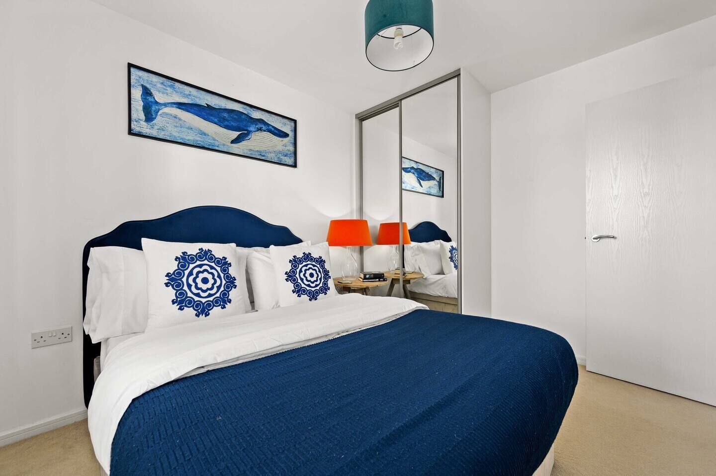 A bedroom with a bed, a nightstand, a lamp, and a mirror.