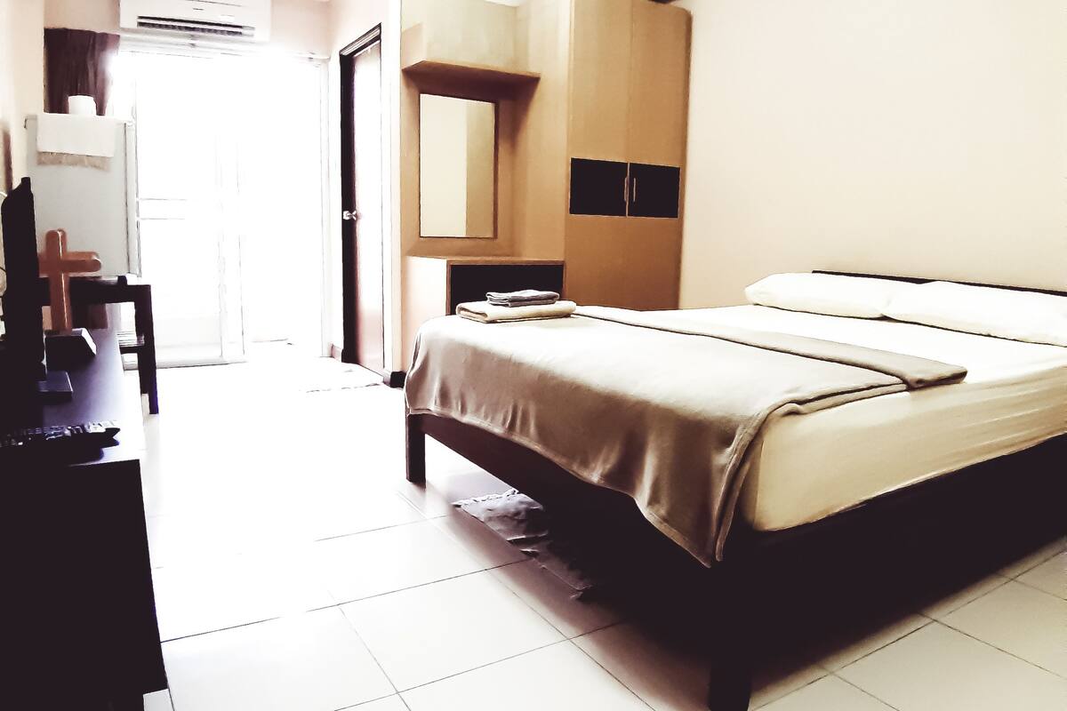 A hotel room with a bed, a desk, and a wardrobe.