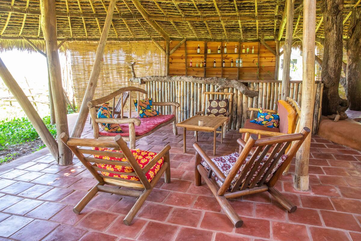 A wooden outdoor seating area with chairs and a table, surrounded by a bamboo structure.