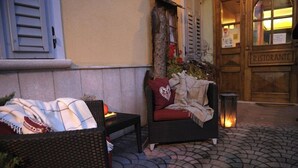 Een terras met rieten meubels, een tafel en een plaid.