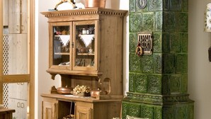 Een klassieke kamer met houten meubels, een groen betegelde open haard en een groot, open boek op de vloer.