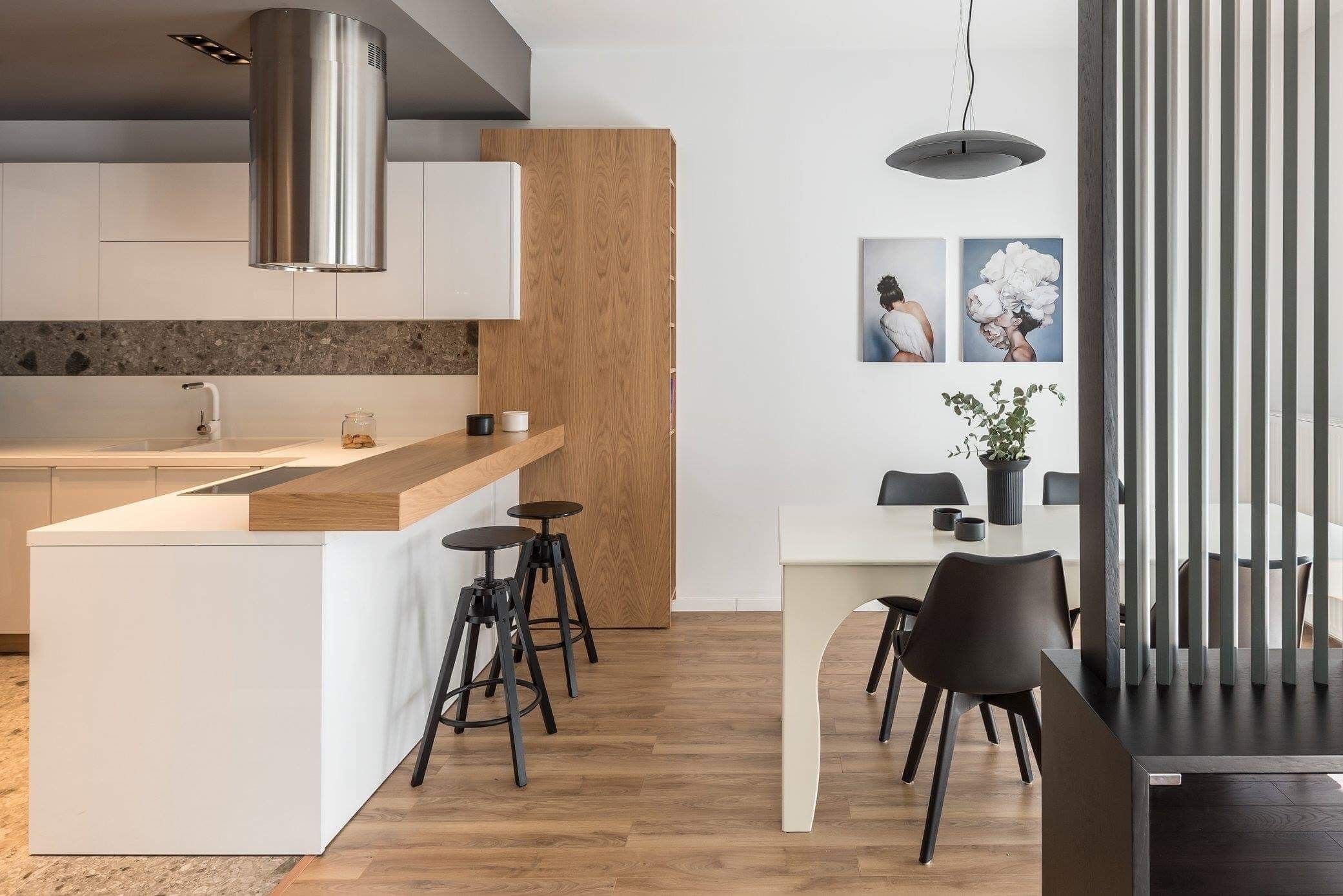 A modern kitchen with a central island, bar stools, and a dining area with a table and chairs.