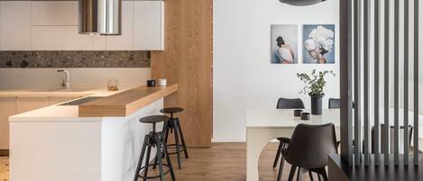 Eine moderne Küche mit einer zentralen Kochinsel, Barhocker und einem Essbereich mit Tisch und Stühlen.