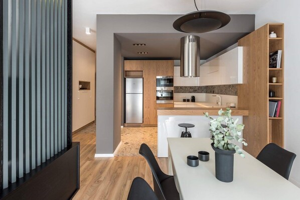 A modern kitchen with stainless steel appliances, a wooden island, and a dining area with a table and chairs.