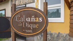 Un letrero rústico con la inscripción "Cabañas del Dique" y "TANDIL", que indica un establecimiento de alojamiento.