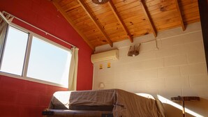 Una habitación con cama altillo, ventana y pared roja.