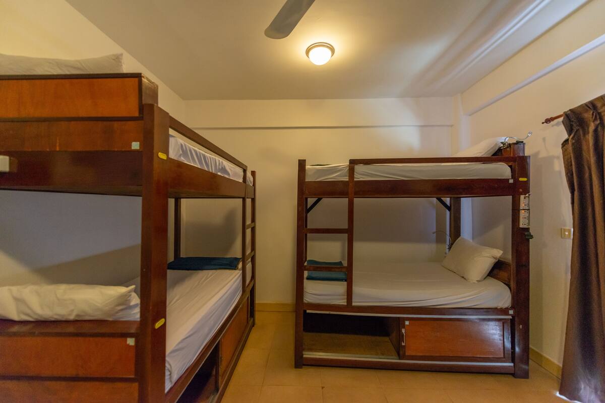 A room with two bunk beds, a ceiling fan, and a light fixture.