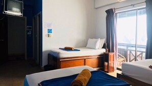 A hotel room with two beds, a TV on a stand, an air conditioning unit, and a window with curtains. - G&Z Plan B Hostel (Siem Reap)