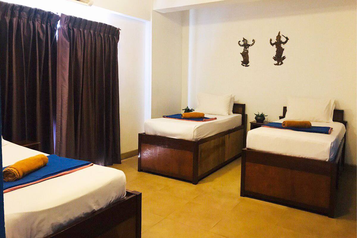 A hotel room with two single beds, a large window with curtains, and a small wall decoration.