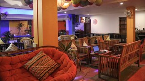 A hotel lobby with wooden furniture, a red sofa, and ceiling fans. - G&Z Plan B Hostel (Siem Reap)