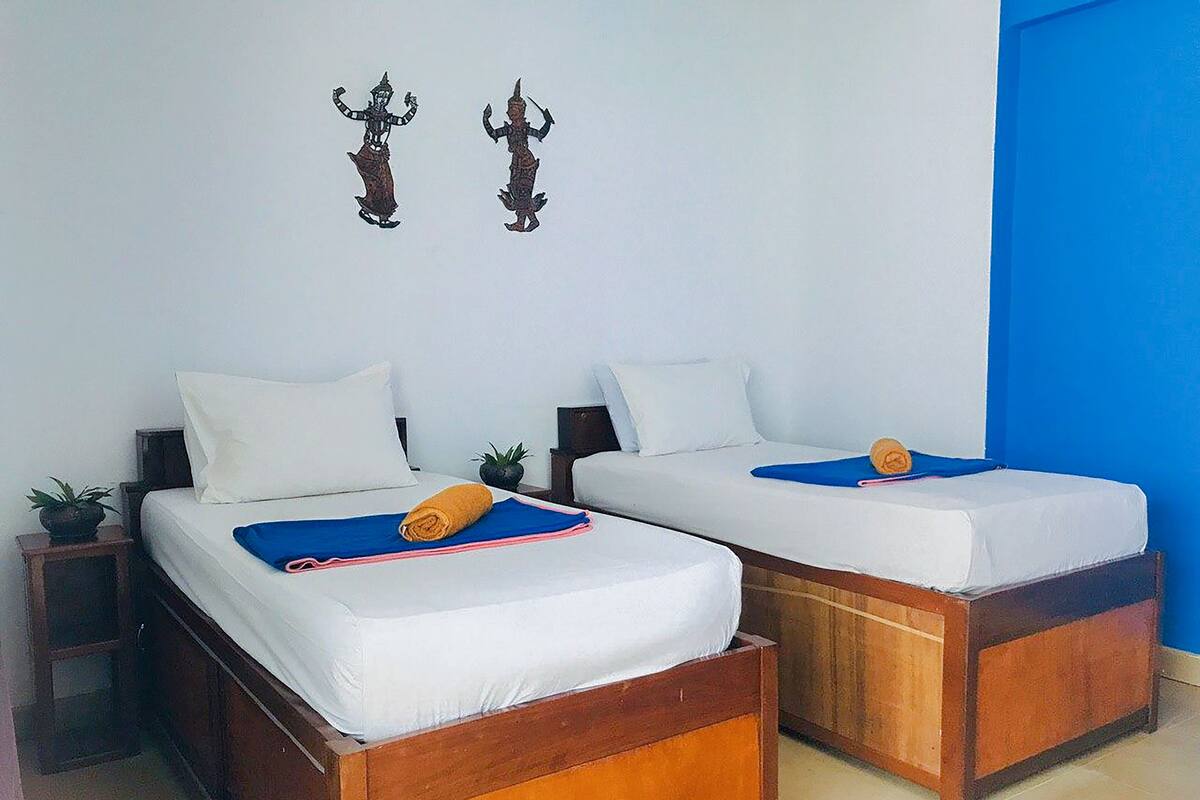 A room with two wooden beds, white bedding, and a blue accent wall.