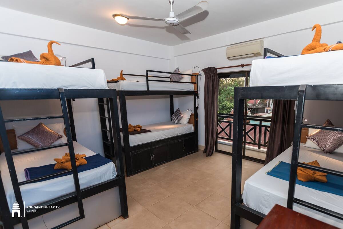 A dormitory room with bunk beds, a ceiling fan, and an air conditioning unit.