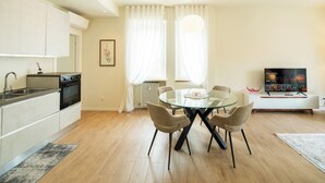 Eine moderne Küche mit Essbereich, ausgestattet mit einem Glastisch, Stühlen, einem Fernseher und einer Heizung.
