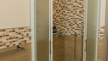 Eine barrierefreie Dusche mit Glastür, Duschbrausehandstück und integriertem Bidet.