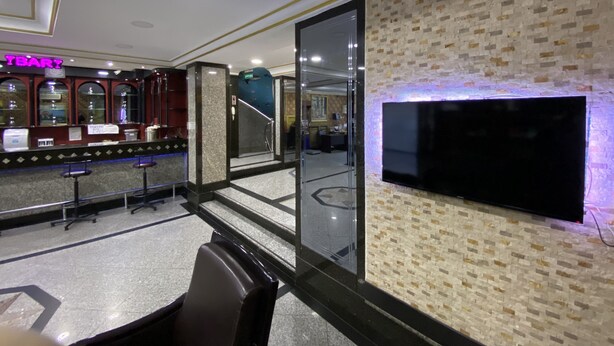 A hotel lobby with a bar area, a staircase, and a flat-screen TV mounted on a textured wall. - Grand Oral Hotel (Istanbul)