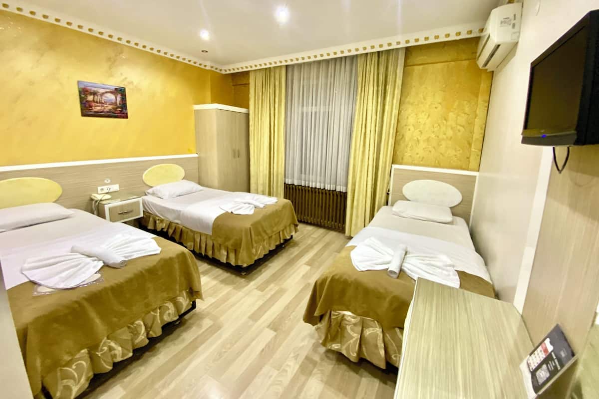 A hotel room with two single beds, a wardrobe, a television, and a painting on the wall.