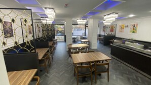 A modern restaurant interior with wooden tables and chairs, decorative wall panels, and pendant lighting. - Grand Oral Hotel (Istanbul)