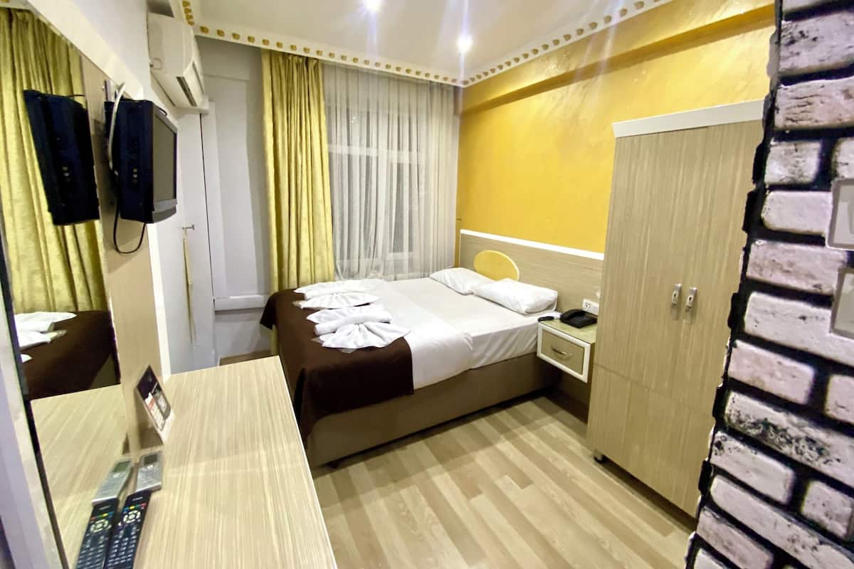 A hotel room with a bed, bedside table, and a wardrobe.