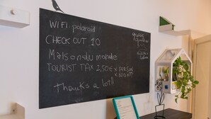 A blackboard with a list of amenities including WIFI, check-out time, and a tourist tax. - Τhe welcoming Rocchetto residence at 25m from P. Erbe (Verona)