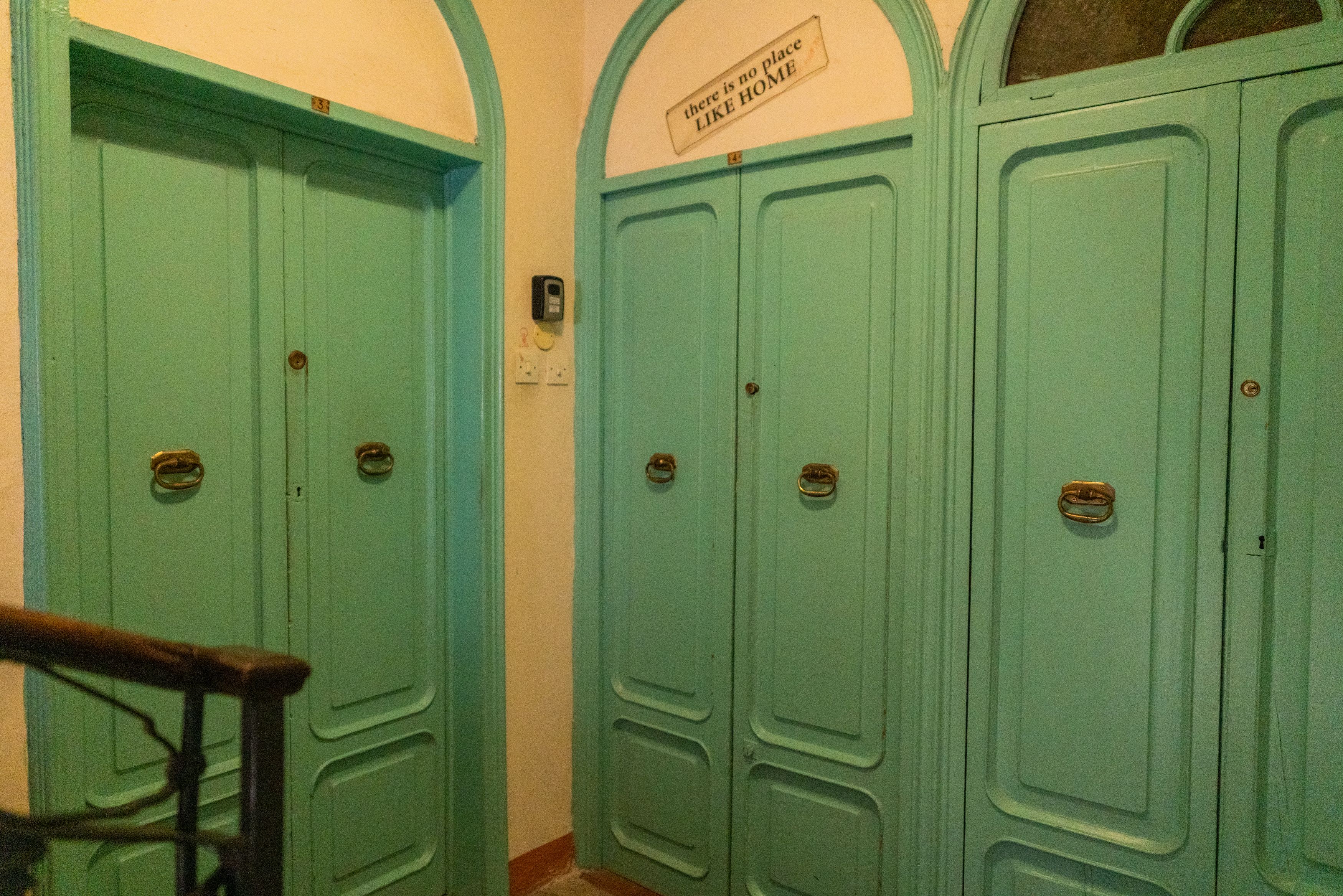 A set of teal-colored doors with a sign above stating "there is no place like HOME."