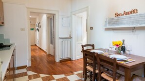 A dining area with a checkered floor, wooden chairs, a table set for two, and a wall-mounted sign that reads "Bon Appetit". - Τhe welcoming Rocchetto residence at 25m from P. Erbe (Verona)
