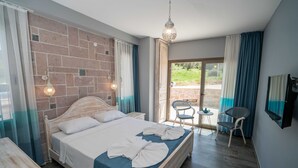 A bedroom with a bed, a small table, chairs, a TV, and a view of the outdoors. - Cunda Mira Butik Otel (Ayvalik)