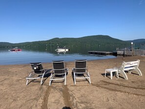 A beach with lounge chairs and a dock with boats. - Condominium Rack Archambo 295 (St-Donat)