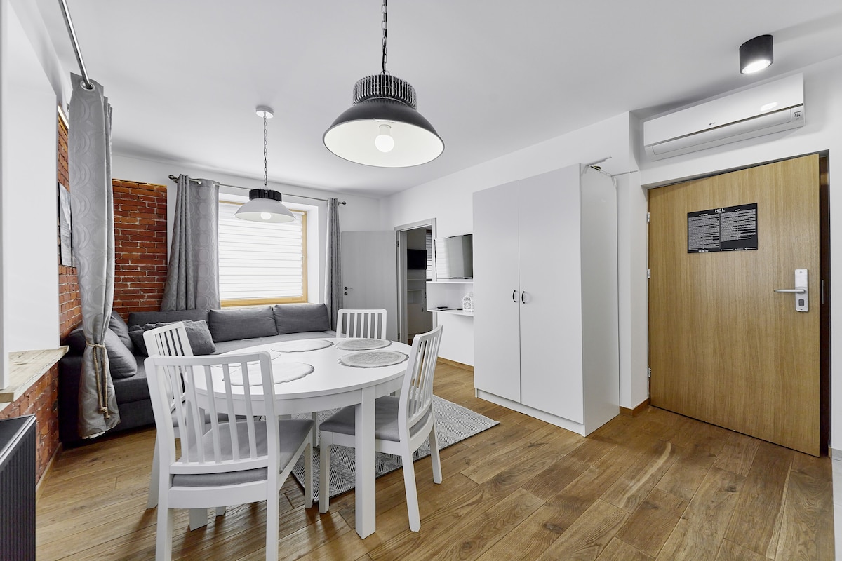 A modern kitchen with white cabinetry, a round dining table, and a hanging pendant light.