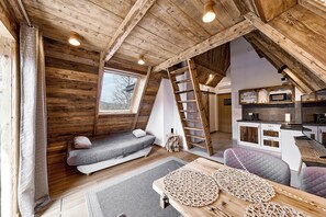 A loft-style room with a loft bed, a ladder, a small kitchenette, and a view through a window. - Hel Apartments (Zakopane)