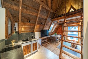 A kitchen with wooden beams, a TV, and a dining area with a view. - Hel Apartments (Zakopane)