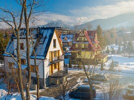 A snow-covered village with traditional houses, a clear sky, and mountains in the background.