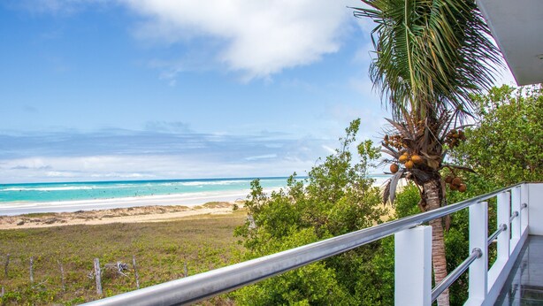Un balcon avec vue sur une plage et l’océan.