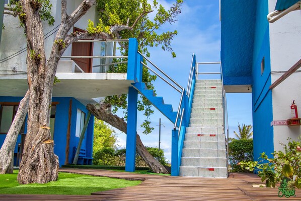 A modern building with blue staircases and railings, a tree, and a grassy area.