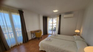 Habitació d'hotel amb un llit, una taula de treball, una cadira, una làmpada i vistes a l'exterior.