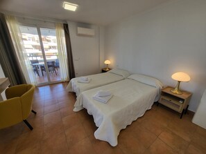 A hotel room with two beds, a chair, a table, and a lamp. - El Rincon 2 (Los Cristianos)