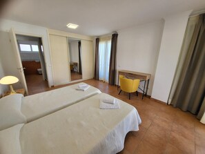 A hotel room with a large bed, a desk, a chair, and a mirror.